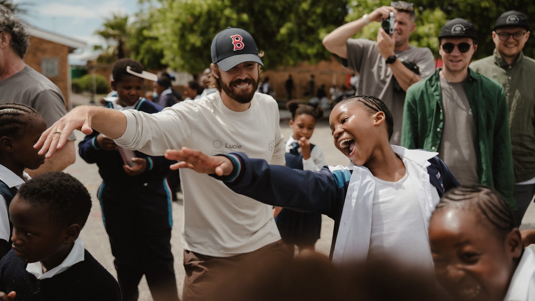 A child dancing with arms outstretched, laughing, next to a visitor mirroring her.