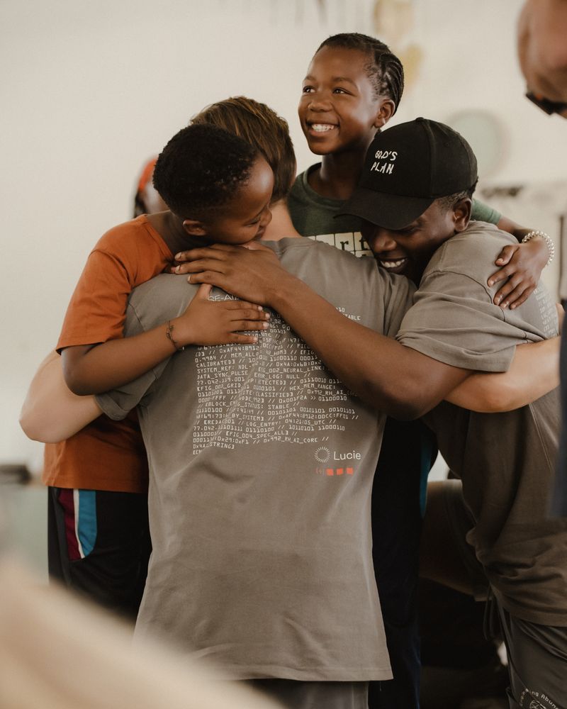Children and visitors in a group hug.