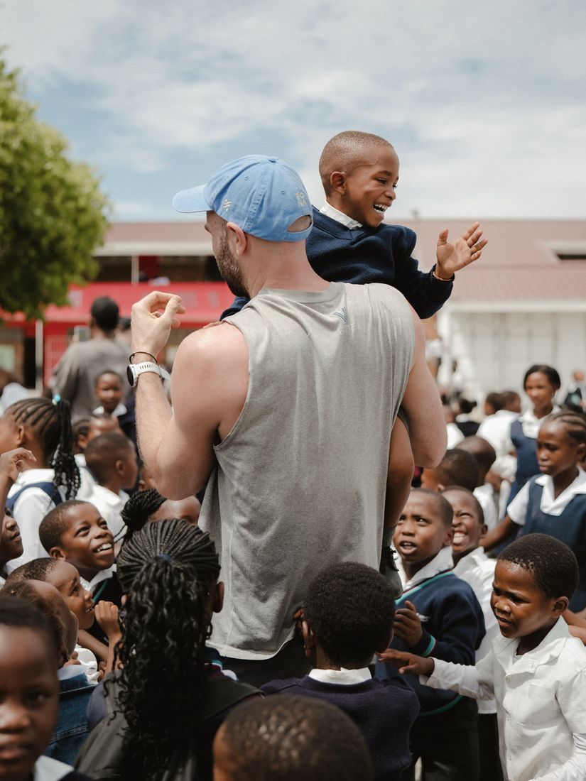 A child sitting on a visitor’s shoulders, laughing above the crowd.